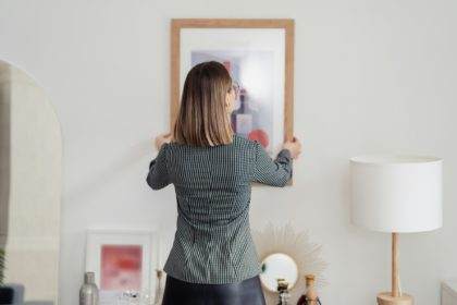 Woman placing a picture on the wall at home