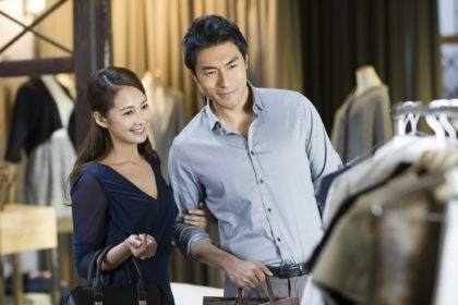 Young couple choosing dress in clothing store