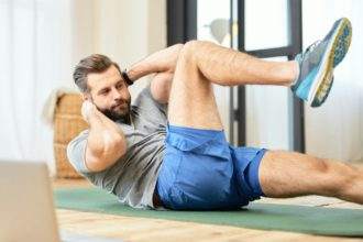 Bearded young man doing abs exercise at home