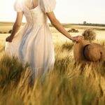Beautiful young bride in white dress is on the agricultural field at sunny day