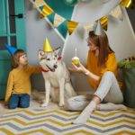 Dog pet birthday party, Happy family mother and child congratulating pet with birthday cupcake