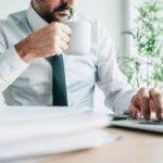 Drinking coffee at work increases productivity, businessman with cup of hot beverage