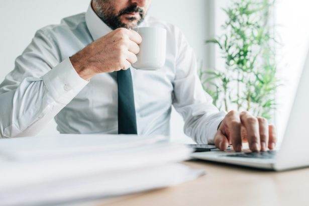 Drinking coffee at work increases productivity, businessman with cup of hot beverage