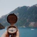 Open rustic compass pointing to the mountains for adventure travel