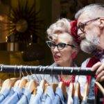 Quirky vintage couple looking at clothes rail in antiques and vintage emporium