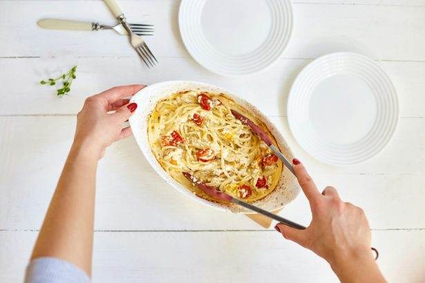 Woman hand's cooking trending viral baked tomatoes and feta with pasta